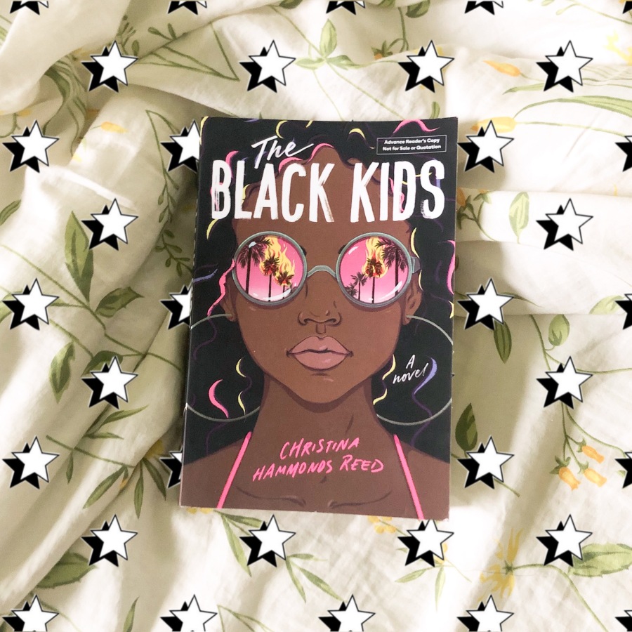 Paperback copy of Christina Hammonds Reed's The Black Kids against a bedspread, surrounded by stars
